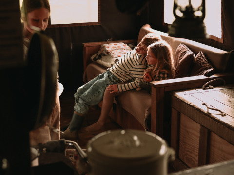 Deux enfants se détendent sur un canapé dans une cabane en bois au BoerenBed Hoeve den Overdraght, Belgique.