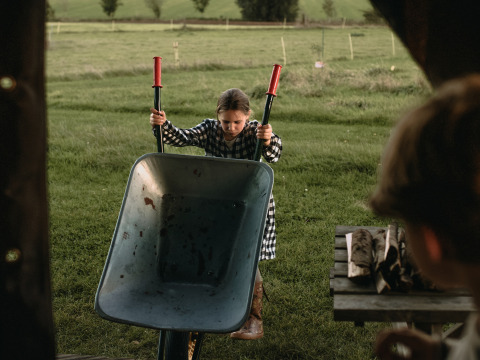 Girl with wheelbarrow at BoerenBed Hoeve den Overdraght holiday park farm in West Flanders, Belgium.