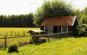 Cascina con tetto rosso e recinto al BoerenBed De Lange Weide, parco vacanze a Drenthe, nei Paesi Bassi.