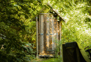 Toilettes rustiques en bois entourées de verdure à BoerenBed De Lange Weide, parc de vacances à Drenthe, Pays-Bas.