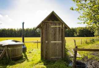 Kleiner Holzschuppen und Badefass auf einer Wiese bei BoerenBed De Lange Weide, Drenthe, Niederlande.