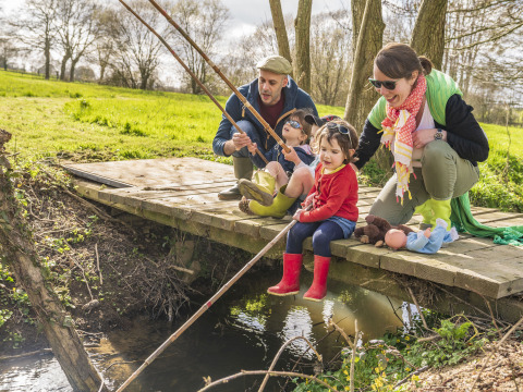 Famiglia che pesca insieme su un ponte di legno a BoerenBed L'Étable des Mauges nei Paesi della Loira.