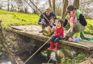 Famiglia che pesca insieme su un ponte di legno a BoerenBed L'Étable des Mauges nei Paesi della Loira.