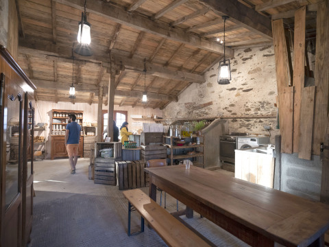 Cucina rustica e zona pranzo con tavolo in legno nel BoerenBed L'Étable des Mauges, Pays de la Loire, Francia.