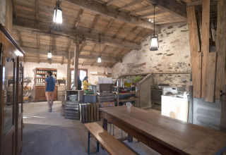 Cucina rustica e zona pranzo con tavolo in legno nel BoerenBed L'Étable des Mauges, Pays de la Loire, Francia.