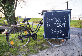 Bicicletta con cartello 'Camping à la ferme ouvert' accanto a una strada in Pays de la Loire, Francia.