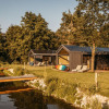 Naturresort Steinwald glamping with tiny houses on a lakeside in Bavaria, surrounded by greenery and trees.