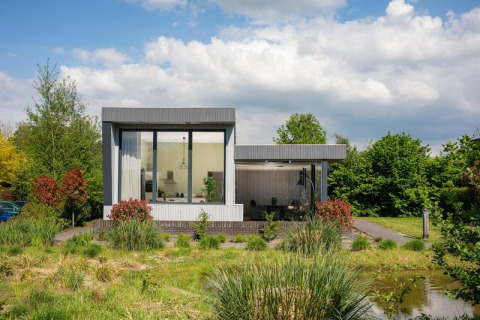 Boslodge Plus moderne avec grandes baies vitrées et terrasse, entourée de verdure à 't Schuttenbelt, Pays-Bas.
