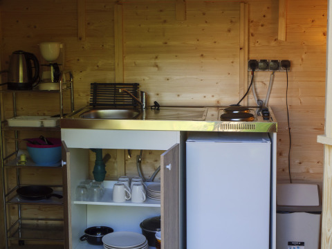 Keukenhoek in een safaritent met gootsteen, kookplaat en servies op Campsite Des Randonneurs, Frankrijk.