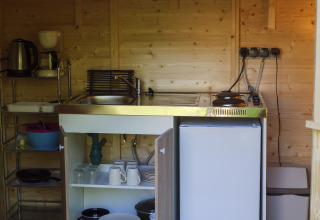 Keukenhoek in een safaritent met gootsteen, kookplaat en servies op Campsite Des Randonneurs, Frankrijk.
