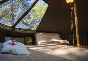 Inside the Inuit Forest Tent at Campsite Des Randonneurs in France, showing the bed, sofa, and skylight view.