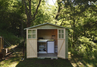 Houten schuurtje met open deuren, keukentje en mini-koelkast in het bos bij Campsite Des Randonneurs, Frankrijk