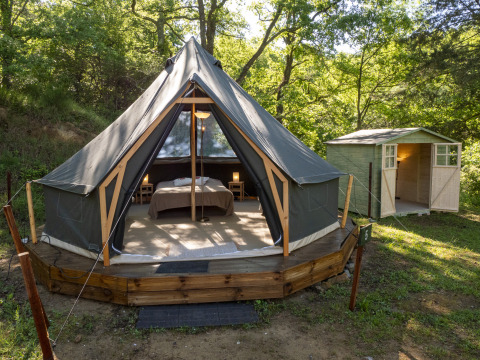 Tenda safari Inuit Forest Tent al Campeggio Des Randonneurs in Francia, con pedana in legno e casetta vicina.