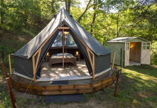 Tenda safari Inuit Forest Tent al Campeggio Des Randonneurs in Francia, con pedana in legno e casetta vicina.