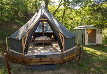 Safari tent Inuit Forest Tent at Campsite Des Randonneurs in France, with wooden deck and nearby forest cabin.
