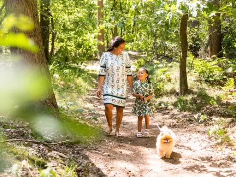 Madre e hija paseando a su perro por el bosque en el parque vacacional Molenvelden, North-Brabant, Países Bajos.