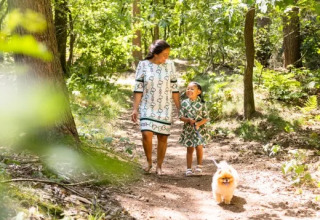 Mutter und Tochter spazieren mit Hund im Wald im Ferienpark Molenvelden, Nordbrabant, Niederlande.