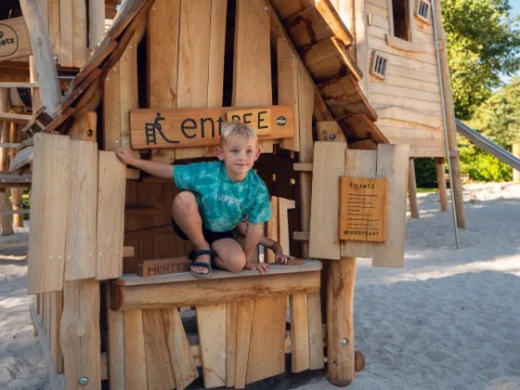 Boy playing inside a wooden playhouse at the playground of Holiday park Molenvelden, North-Brabant, Netherlands.