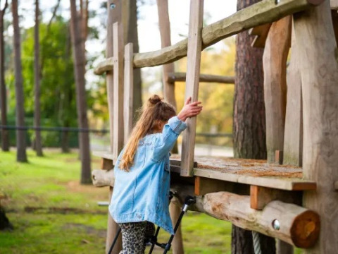Una niña sube a un parque infantil de madera en Holiday park Molenvelden, rodeada de árboles en Brabante Septentrional.