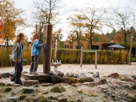 Due bambini giocano vicino a una pompa d’acqua nel parco giochi del villaggio turistico Molenvelden nel Brabante Settentrionale, Paesi Bassi.