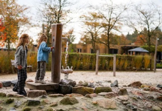 Zwei Kinder spielen an einer Wasserpumpe auf dem Spielplatz im Ferienpark Molenvelden in Nordbrabant, Niederlande.