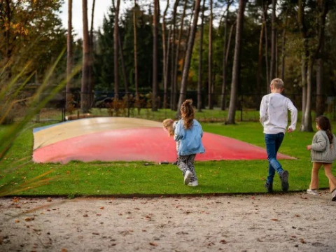 Bambini corrono verso un cuscino saltellante colorato al parco vacanze Molenvelden, North-Brabant, Paesi Bassi.