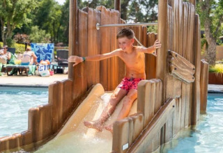 Boy enjoying a water slide in the swimming pool at Holiday Park Molenvelden, North Brabant, Netherlands.