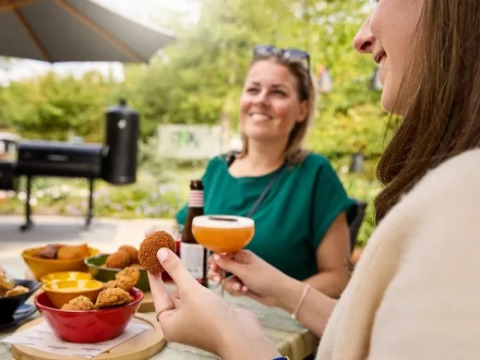 Two women enjoying snacks and drinks outdoors at Holiday park Molenvelden in North Brabant, Netherlands.