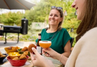 Dos mujeres disfrutan de aperitivos y bebidas al aire libre en el parque Holiday Molenvelden, Brabante Septentrional.