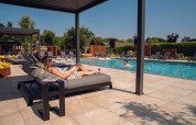 Mujer relajándose en una tumbona junto a la piscina en el parque vacacional Molenvelden, Brabante Septentrional, Países Bajos.