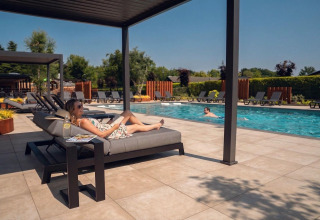 Frau entspannt auf einer Liege am Pool im Ferienpark Molenvelden, Nord-Brabant, Niederlande.