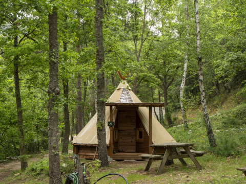 Modern Tipi-tent bij Campsite Des Randonneurs in Frankrijk, omgeven door groen bos en picknicktafel.