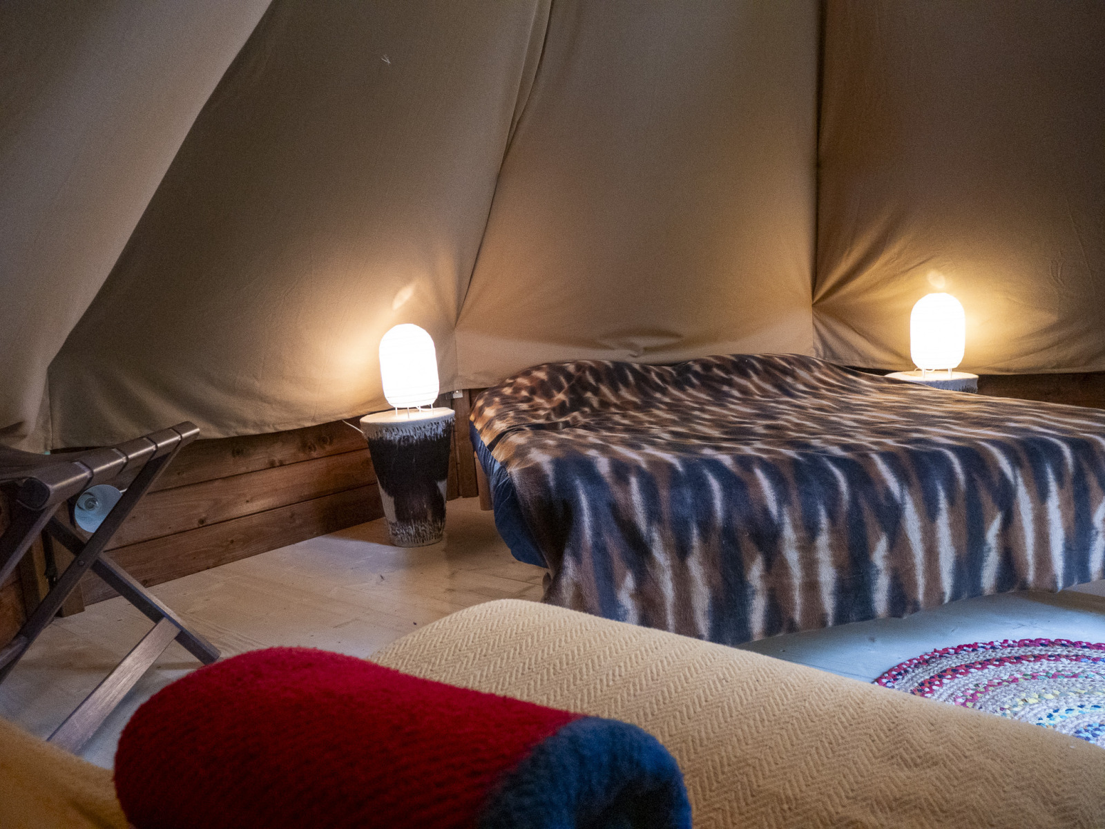 Interieur van een modern tipitent op Campsite Des Randonneurs in Frankrijk, met bed, lampen en gezellige sfeer.