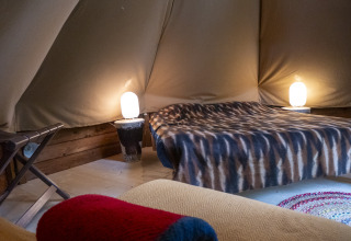 Interieur van een modern tipitent op Campsite Des Randonneurs in Frankrijk, met bed, lampen en gezellige sfeer.