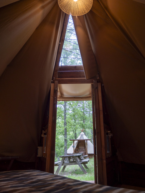 Uitzicht vanuit een moderne tipi op Campsite Des Randonneurs in Frankrijk, met picknicktafel buiten.