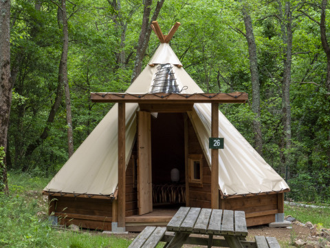 Moderne tipi bij Campsite Des Randonneurs in Frankrijk, omgeven door bomen met picknicktafel ervoor.
