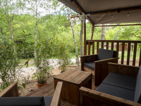 View from the terrace of a Safari Lodge tent with wooden furniture at Campsite Des Randonneurs in France.