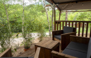 View from the terrace of a Safari Lodge tent with wooden furniture at Campsite Des Randonneurs in France.