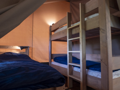 Interno di una tenda Safari Lodge al campeggio Des Randonneurs in Francia, con letti a castello e biancheria.