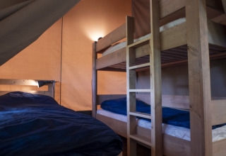 Interno di una tenda Safari Lodge al campeggio Des Randonneurs in Francia, con letti a castello e biancheria.