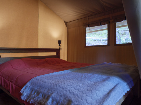 Bedroom interior of Safari Lodge tent at Campsite Des Randonneurs in France, showing a double bed.