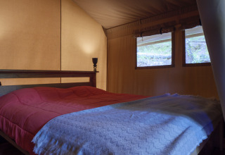 Interno camera da letto della tenda Safari Lodge al Campeggio Des Randonneurs in Francia, letto doppio.