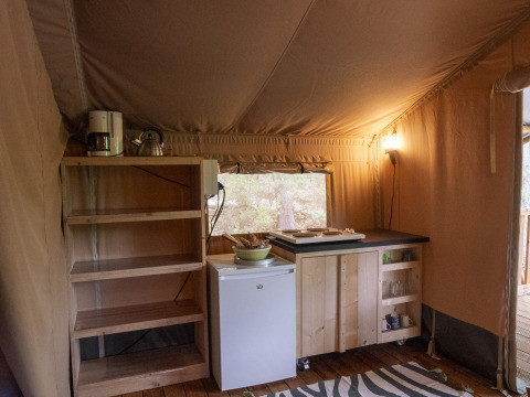 Angolo cucina in una tenda Safari Lodge al Campeggio Des Randonneurs, Francia, con scaffali e mini frigorifero.
