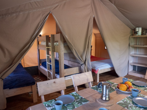 Interno di una tenda safari lodge al campeggio Des Randonneurs in Francia con letti a castello e tavolo.