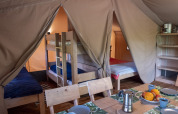 Interior of a safari lodge tent at Campsite Des Randonneurs in France featuring bunk beds and a table.