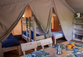 Interior of a safari lodge tent at Campsite Des Randonneurs in France featuring bunk beds and a table.
