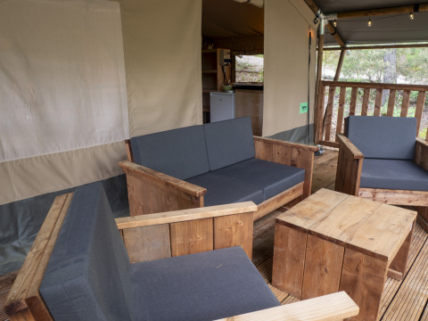 Safari Lodge al campeggio Des Randonneurs con sedute in legno, cuscini grigi e zona relax esterna.