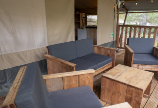 Safari Lodge at Campsite Des Randonneurs with wooden seating, grey cushions, and outdoor relaxation area.