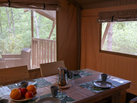 Inside view of Safari Lodge at Campsite Des Randonneurs, France, with set dining table and woodland view.