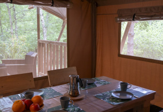 Vista interna della Safari Lodge al Campsite Des Randonneurs, Francia, con tavolo apparecchiato e natura.